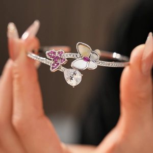 Detail view of silver butterfly bangle with pink zircon stones and pear shaped drop