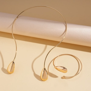 Detail of minimalist gold polished teardrop collar and matching open cuff bracelet set