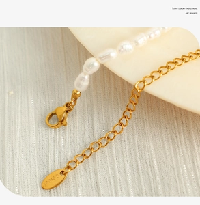 Detailed macro view of the gold lobster clasp and round S.Steel tag on the pearl necklace