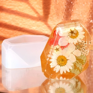 Detail of faceted stone silicone mold and resin casting with dried flowers inside