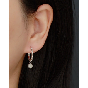 Macro detail of S925 sterling silver hoop earring with sunburst round pendant on model