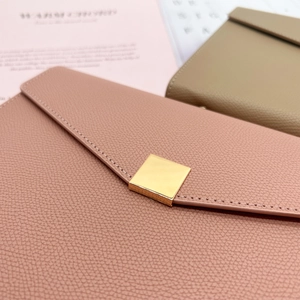 Close-up of pink and khaki lychee grain leather notebooks with golden metal square buckles