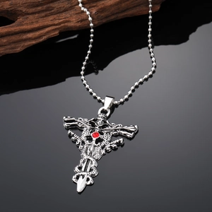 Detail of silver cross pendant with red gemstone, skull and snake relief on beaded chain