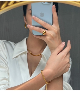 Polished gold twisted necklace and U-shaped earrings worn with a white silk shirt