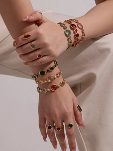 Close-up of bohemian gold bracelets and rings set with colorful crystal gemstones