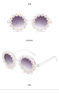Detail view of round floral kids sunglasses with white daisy frames and purple gradient lenses