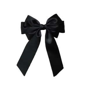 Detail of a black double-layered satin bow hair clip with premium silk texture and glossy finish