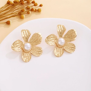 Detailed view of vintage gold flower earrings with a centered white pearl inlay