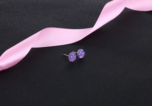 Macro shot of purple round crystal cluster stud earrings on textured black background