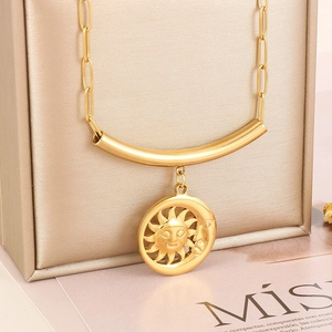 Détail d'un pendentif soleil et lune doré sur chaîne trombone et boîte à bijoux