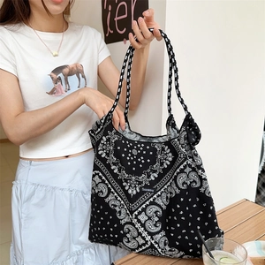 Close-up of a large black paisley floral tote bag worn on a woman's shoulder in daily life
