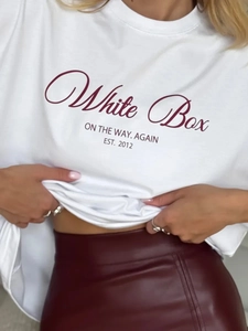Κοντινό πλάνο λευκού βαμβακερού T-shirt με μπορντό τύπωμα και κόκκινη δερμάτινη φούστα