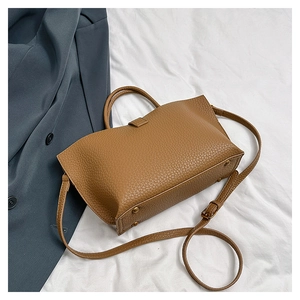 Detail of brown litchi pattern PU leather tote bag with protective metal feet on base