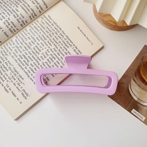 Dettaglio di una molletta rettangolare viola opaco su un libro aperto
