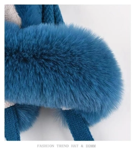 Close-up of fluffy faux fur trim and knit texture on this dark blue winter earflap hat