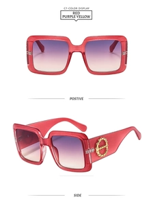 Detail of oversized square sunglasses with red frames, gradient lenses, and gold temples