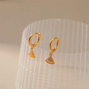Macro detail of gold plated fan-shaped earrings with zircon inlay on frosted stand