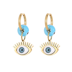 Detail of gold hoops featuring blue evil eye beads and decorative eyelashes pendants