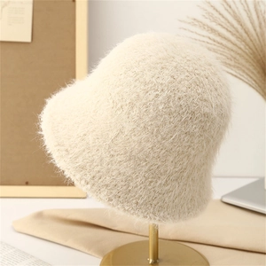 Detail of soft cream plush bucket hat texture on a minimalist gold display stand