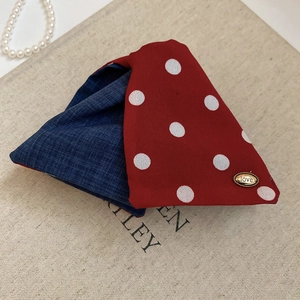 Close-up of polka dot fabric scrunchie with denim texture and gold Love metal tag