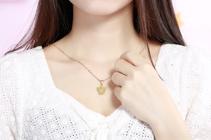 Dettaglio di una collana con ciondolo angelo dorato e catena a sfere su una modella