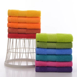 Colorful set of soft absorbent cotton square towels stacked on a white wire rack