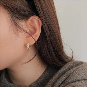 Close-up of gold hoop earrings with sparkling oval cubic zirconia on a female model