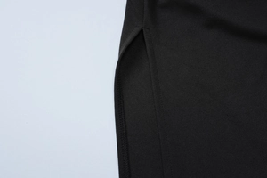 Close-up of the black dress fabric texture with side slit detail and neat stitching