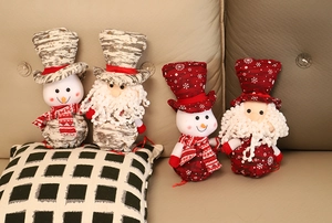 Plush Christmas dolls including Santa and snowmen on a beige sofa for holiday decor