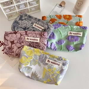 Detailed view of floral jacquard makeup bags with zipper and textured fabric patterns