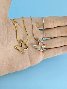 Detailed shot of hollow butterfly pendants in gold and silver on fine snake chains