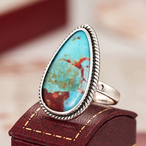 Detalle macro del anillo de gota con piedra azul y borde de plata trenzada vintage