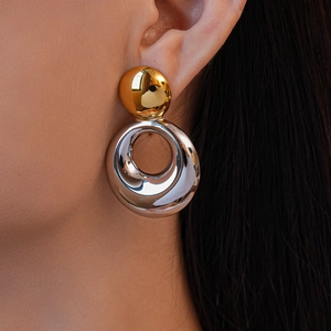Gros plan de boucles d'oreilles pendantes bicolores géométriques style industriel