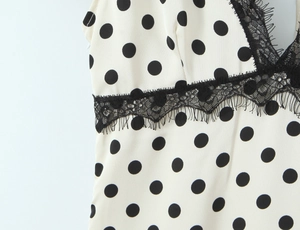 Detailed macro view of white polka dot fabric with black lace trim on the V-neckline dress