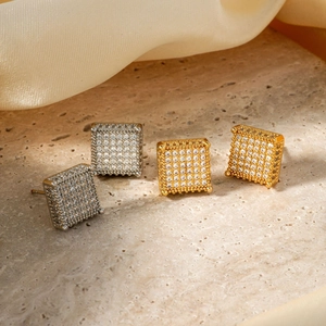 Elegant gold and silver square copper studs with sparkling zircons on a stone plate