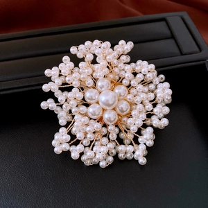 Dettaglio macro di una spilla a fiore fatta a mano con perle bianche e filo d'oro