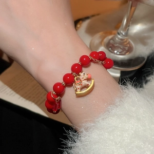 Detail of red beaded bracelet featuring a gold rocking horse charm with enamel inlay