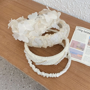 Top view of cream white pearl and mesh bow headbands collection on a wooden surface