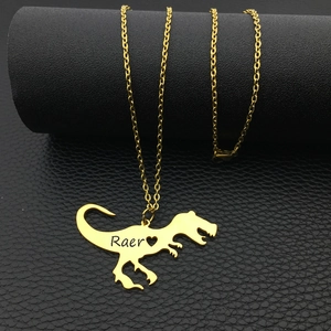 Dettaglio della collana dorata con sagoma di dinosauro e incisione Raer personalizzata