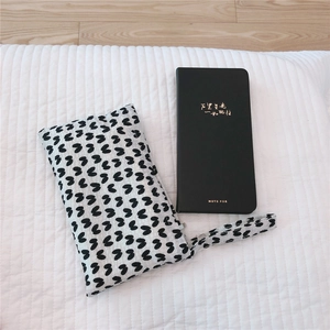 Close-up of a mini polka dot cotton pouch paired with a black gold-stamped notebook