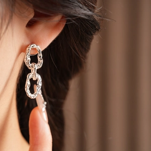 Gros plan d'une femme portant des boucles d'oreilles argentées ovales plissées de luxe