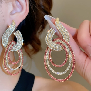 Detail of gold layered oval drop earrings featuring pink and white zircon stones
