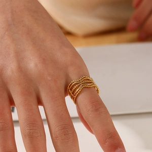 Elegant gold wavy tiered ring with beaded edges on female hand model close-up