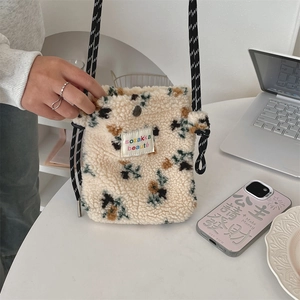Detail of plush floral crossbody bag with woven strap and branded cloth label