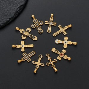 Set mit neun goldenen Kreuzanhängern aus Edelstahl mit Strass auf dunklem Stein