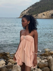 Detail of light pink tiered ruffled dress featuring a silver starfish metal buckle