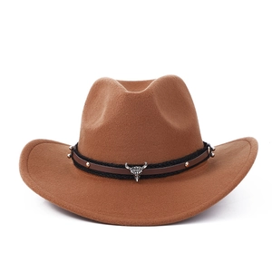 Detail of brown felt cowboy hat featuring silver bull skull ornament and studded leather band