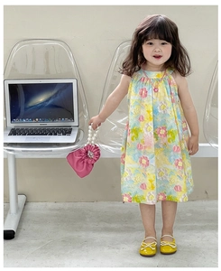 Close-up of children's sleeveless floral dress with pink pearl handbag and cotton fabric