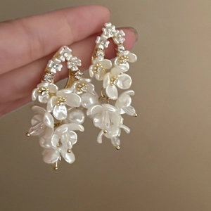 Detail of white shell flower earrings with shimmering rhinestones and long tassel drops