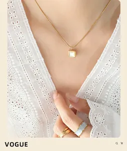 Gros plan du collier doré avec pendentif carré en nacre porté par le mannequin